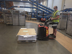 A person using a pump truck to transport a pallet of materials