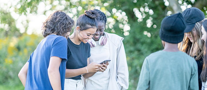 A group of teenagers looking at a phone screen