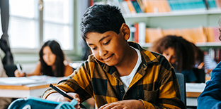 Student in a classroom writing notes