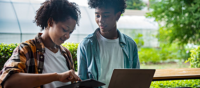 Young students studying outdoor using technology